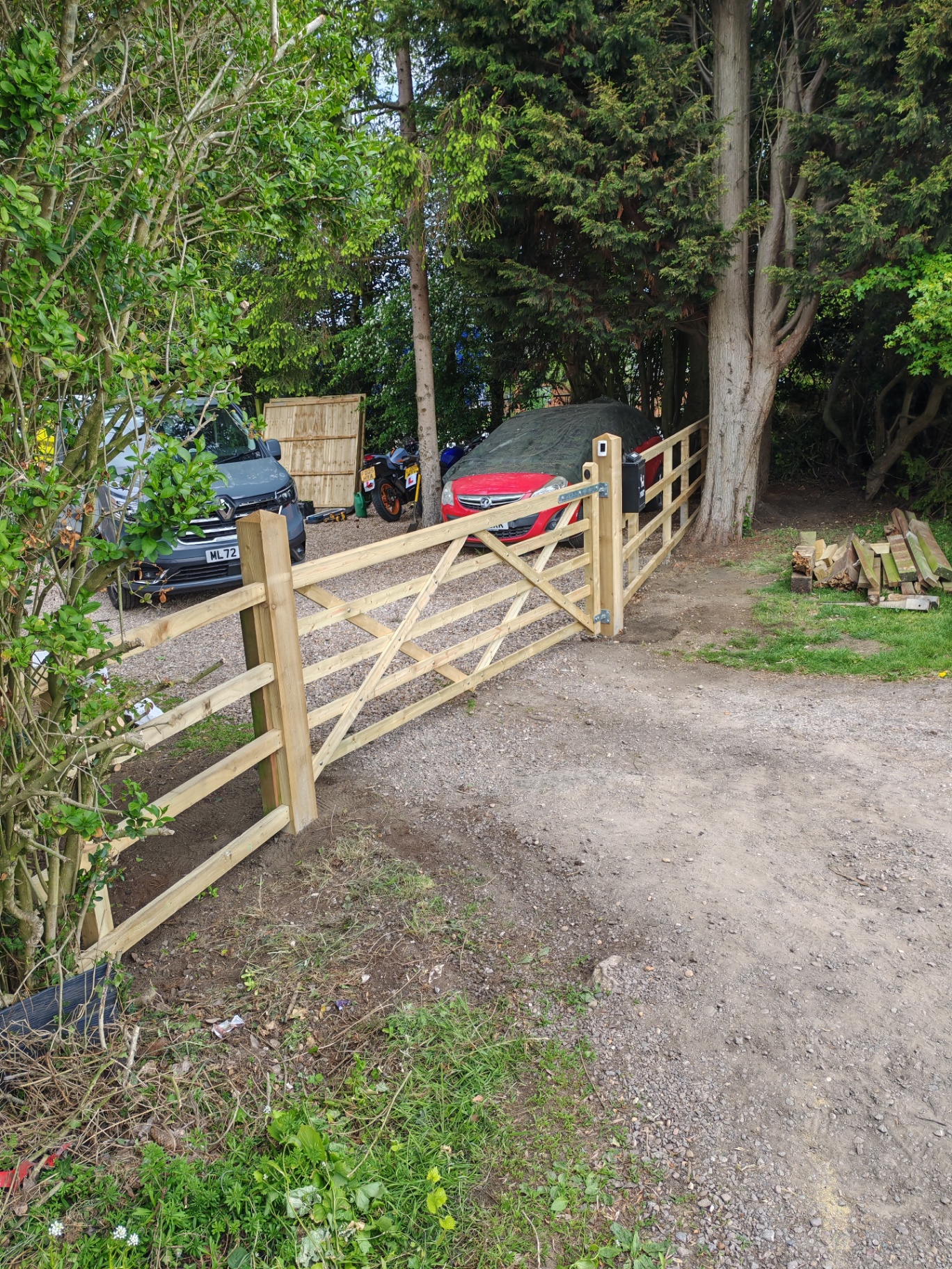 Completed post-and-rail fence with five-bar gate — driveway view